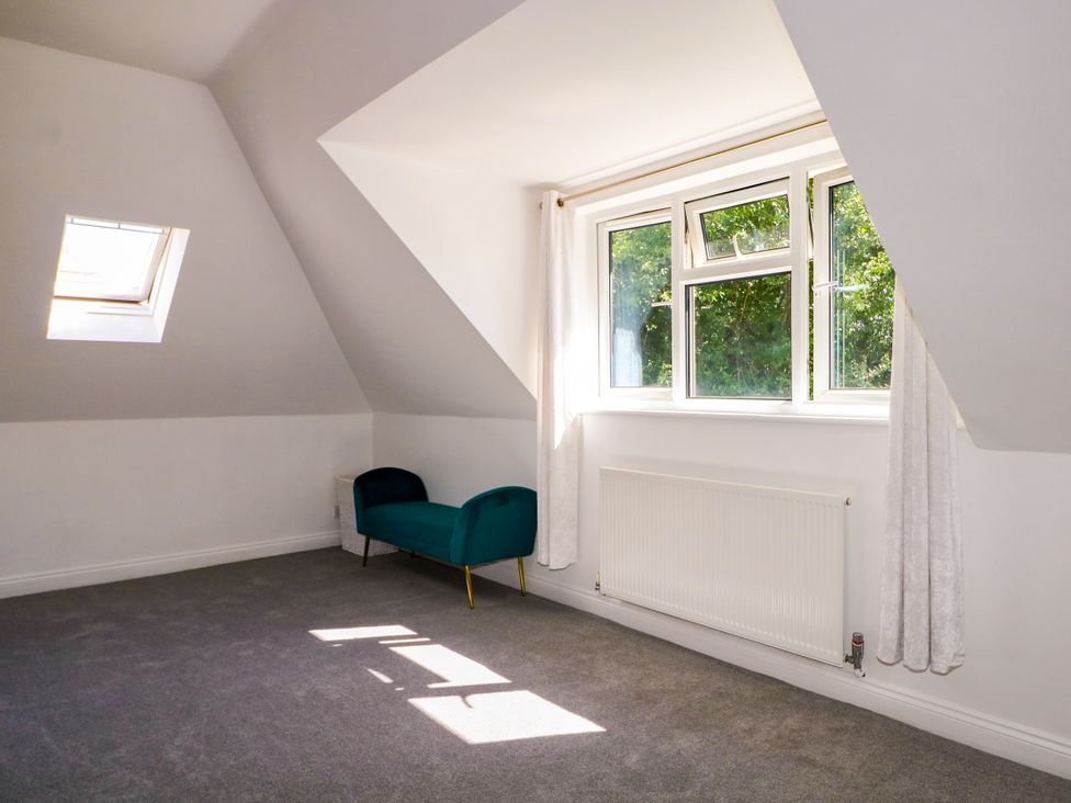 An attic room with a window and an armchair at Lucerne Cottage in Dorking