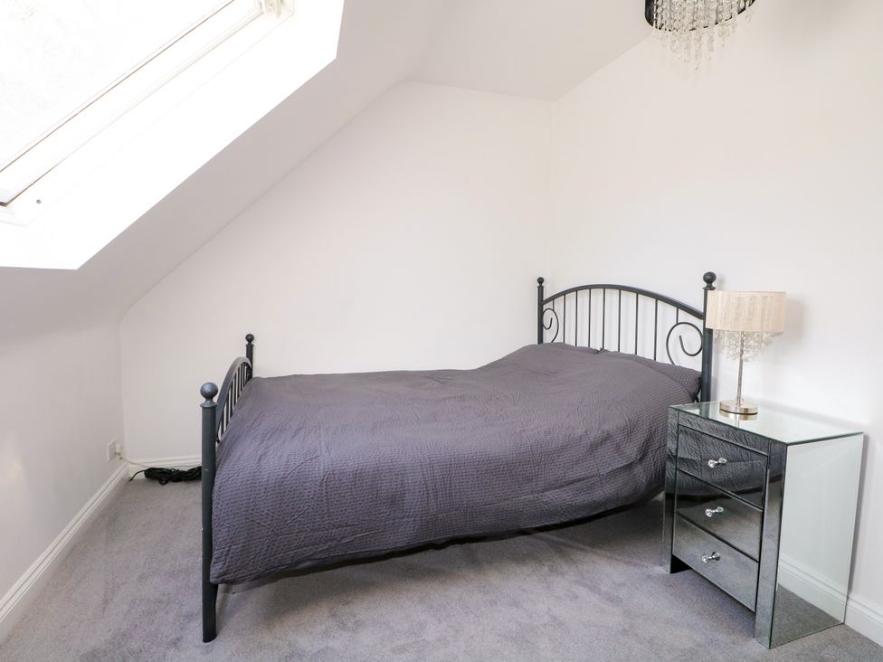 A bedroom with a bed and nightstand at Lucerne Cottage in Dorking