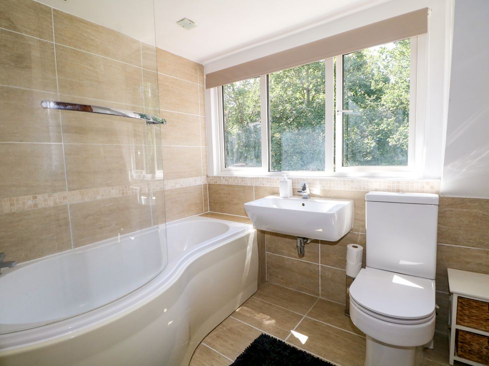 A bathroom with bath tub, toilet and sink at Lucerne Cottage in Dorking