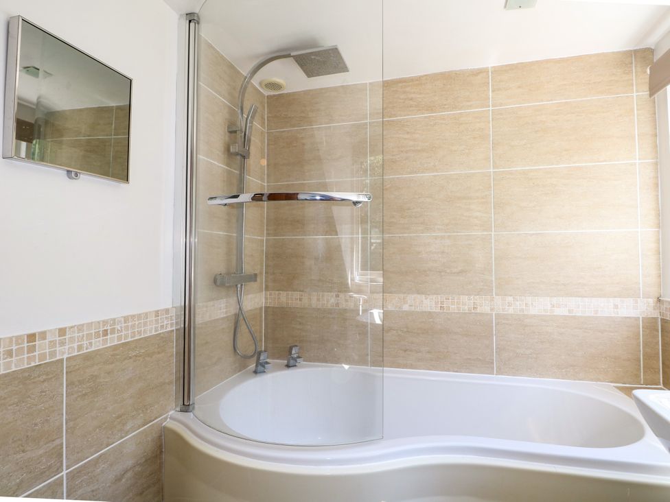 A bathroom with a shower and bathtub at Lucerne Cottage in Dorking