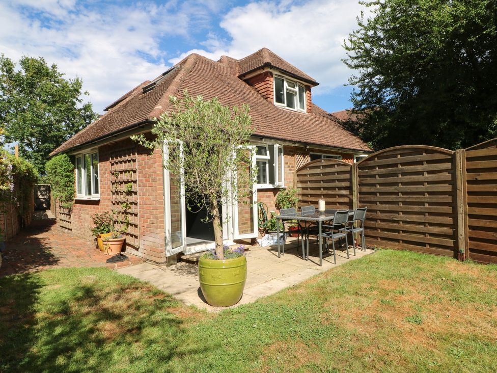 A garden with a house and outdoor seating at Lucerne Cottage in Dorking