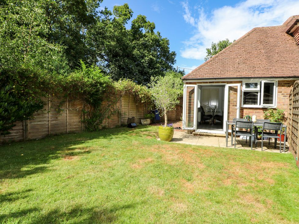 A garden with grass and patio chairs at Lucerne Cottage in Dorking