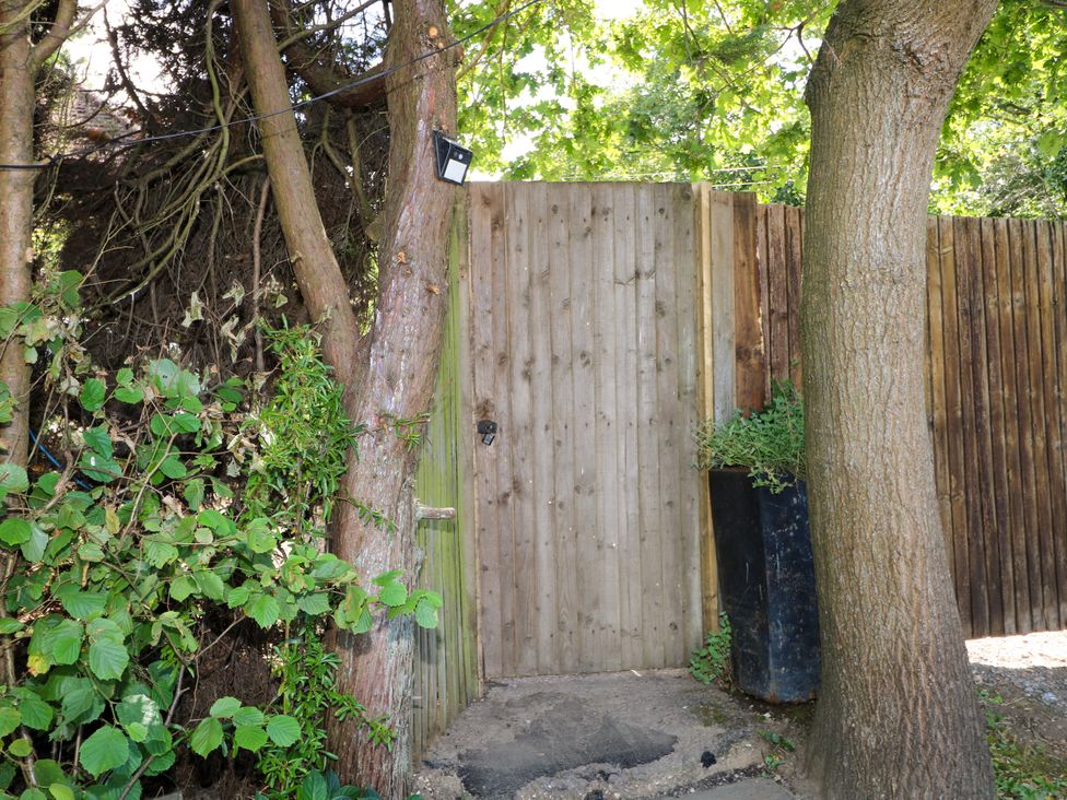 A wooden gate between trees in an outdoor area at Lucerne Cottage Dorking