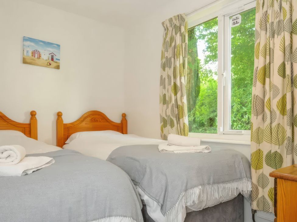 A bedroom with two beds and a window at 9 Honicombe Park in Callington