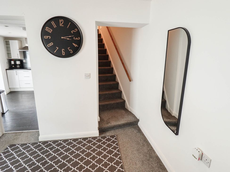 A hallway with a clock and mirror leading to the stairs at Number 3 Old Boston Road