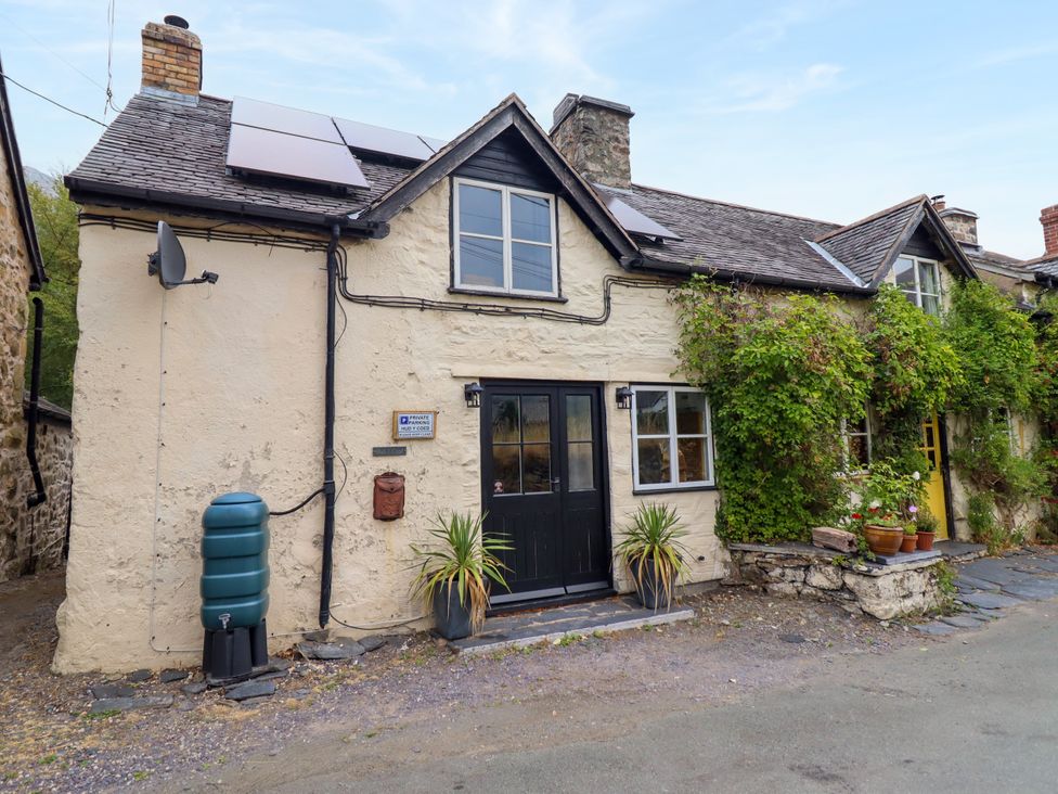 A cottage exterior with solar panels and plants at Hud Y Coed in Llangynog
