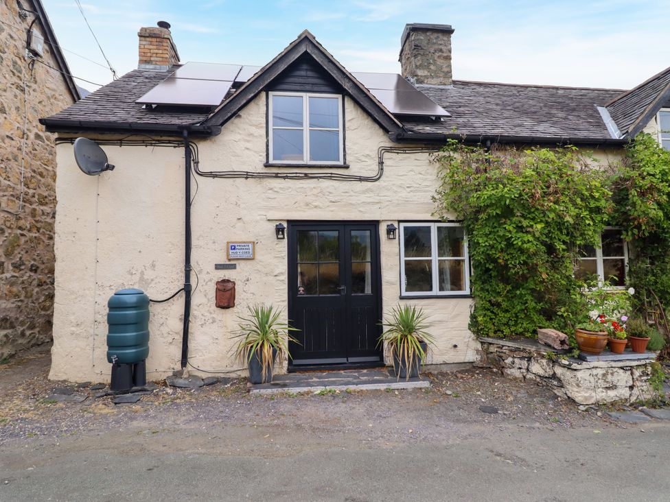 An outdoor view of a cottage with a front door and plants at Hud Y Coed in Llangynog