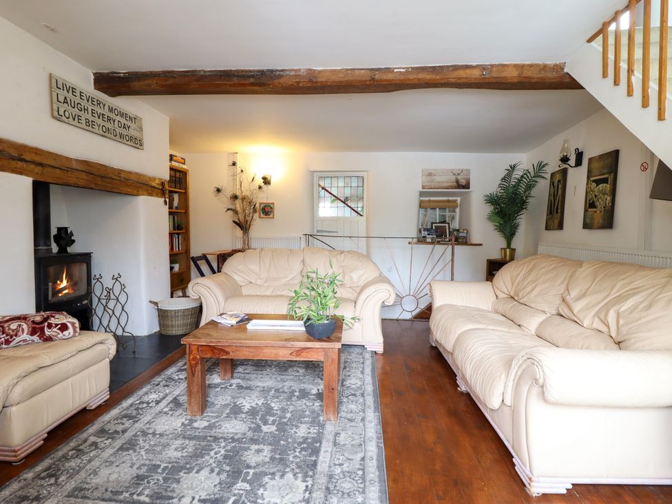 A living room with a fireplace and a coffee table at Hud Y Coed in Llangynog