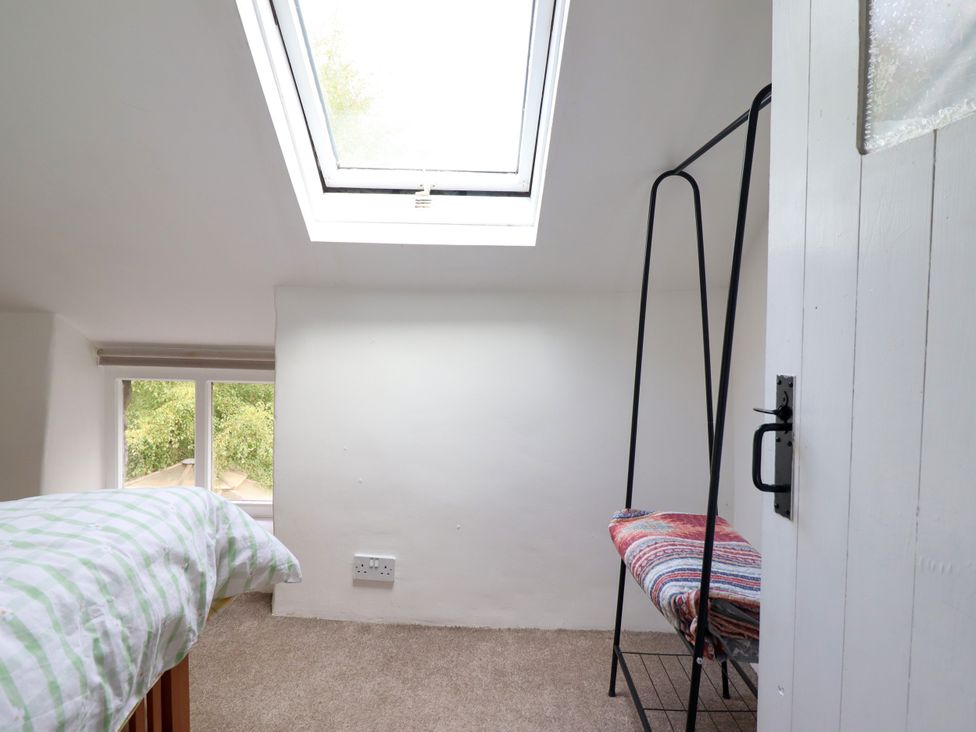 A bedroom with a bed, skylight, and a clothes rack at Hud Y Coed in Llangynog