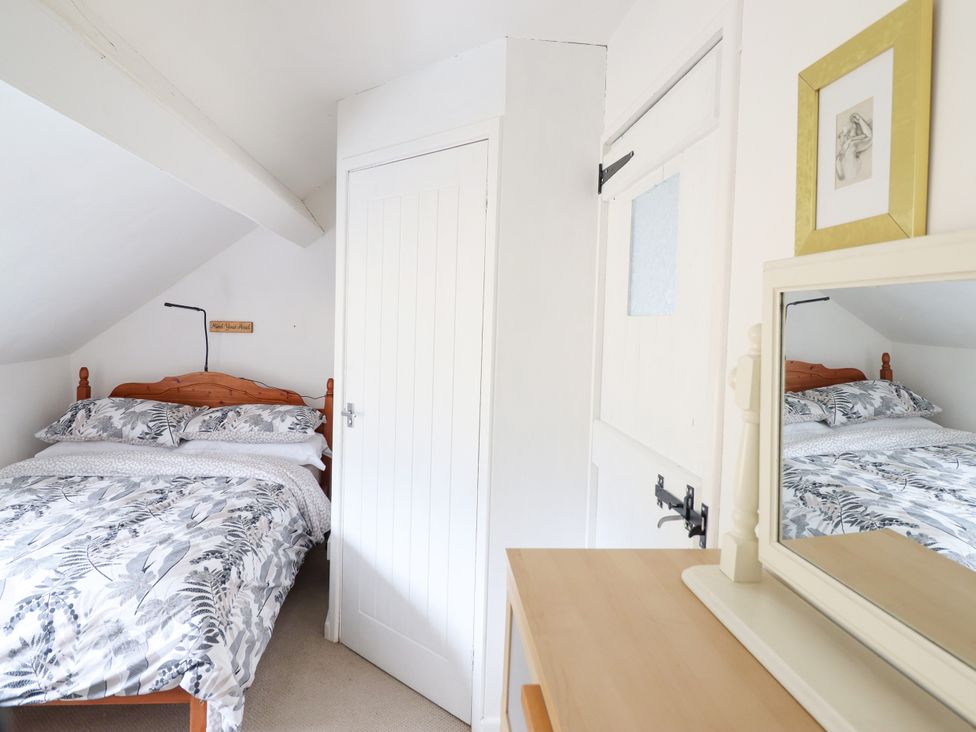 A bedroom with a bed and a dresser at Hud Y Coed in Llangynog