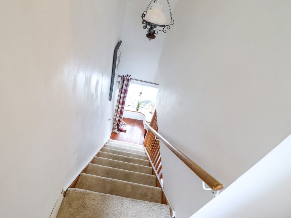 A staircase with a handrail and a lamp in a stairwell at Hud Y Coed Llangynog