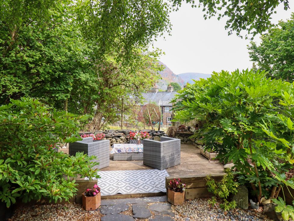 A garden with seating and flower pots at Hud Y Coed in Llangynog