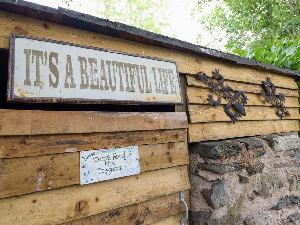 A wooden shed with a sign and decorations at Hud Y Coed in Llangynog