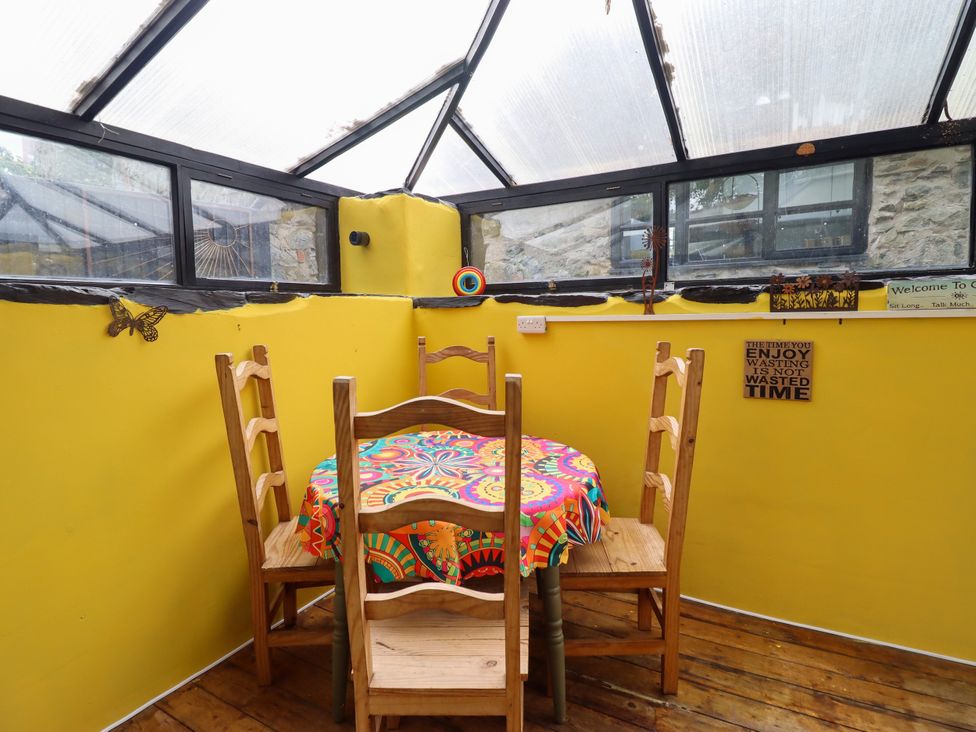 A conservatory with a table and chairs at Hud Y Coed in Llangynog