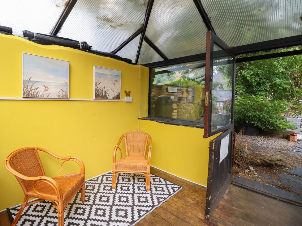 A conservatory with two chairs and paintings at Hud Y Coed in Llangynog