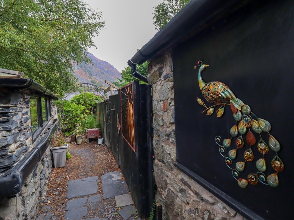 A pathway with a decorative peacock on a gate at Hud Y Coed Llangynog