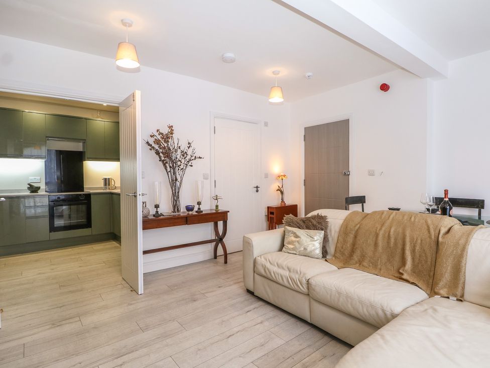 A living room with a sofa and kitchen access at 1 Bed in Bishop's Waltham
