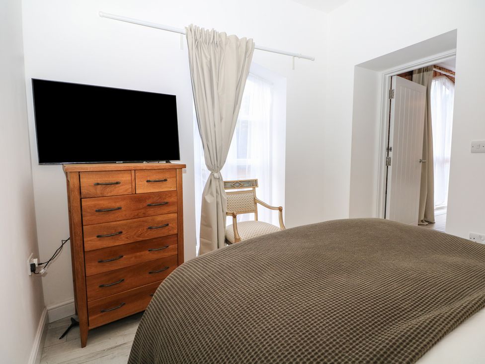 A bedroom with a television, dresser, bed and chair at 1 Bed in Bishop's Waltham