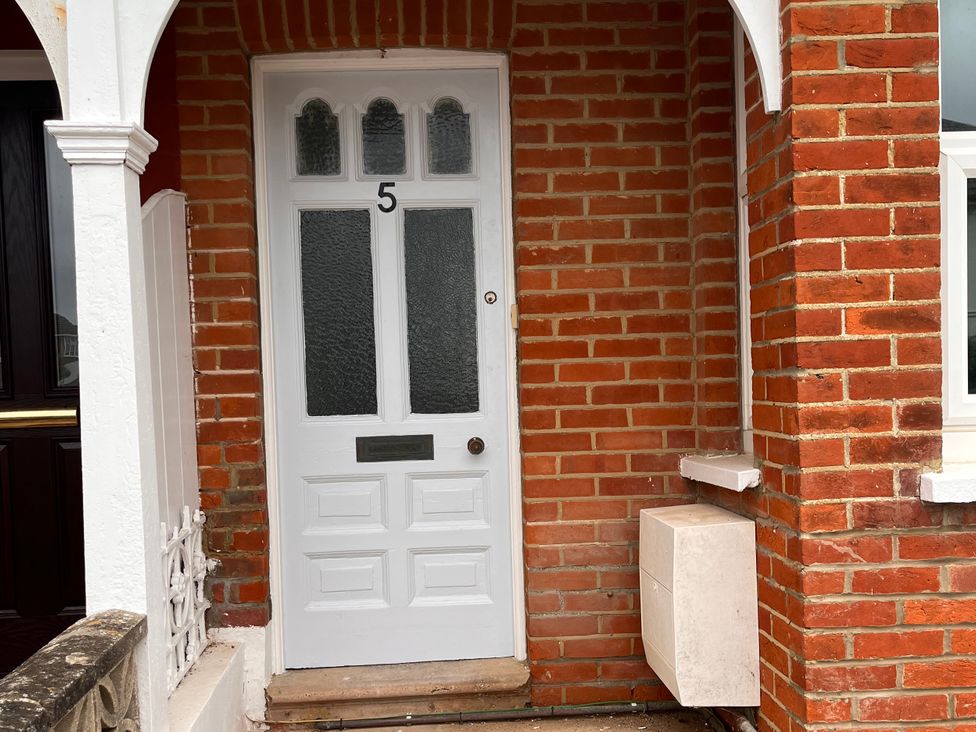 An entrance with a white door and brick wall at 5a Bramber Road in Seaford