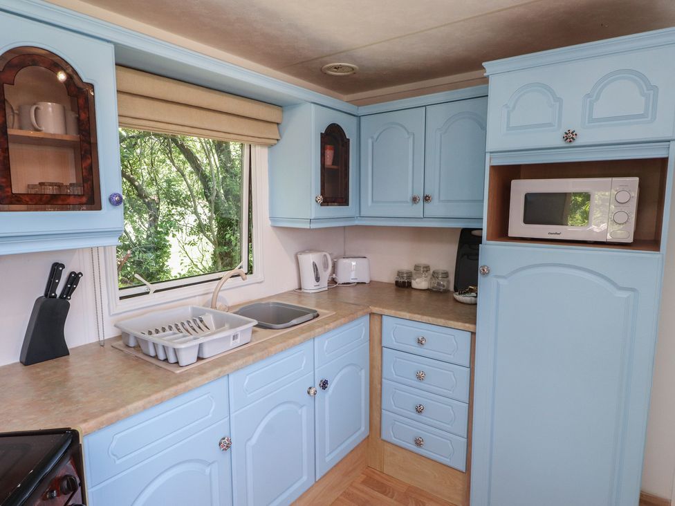 A kitchen with blue cabinets and appliances at Mor a Mynydd in Pwllheli