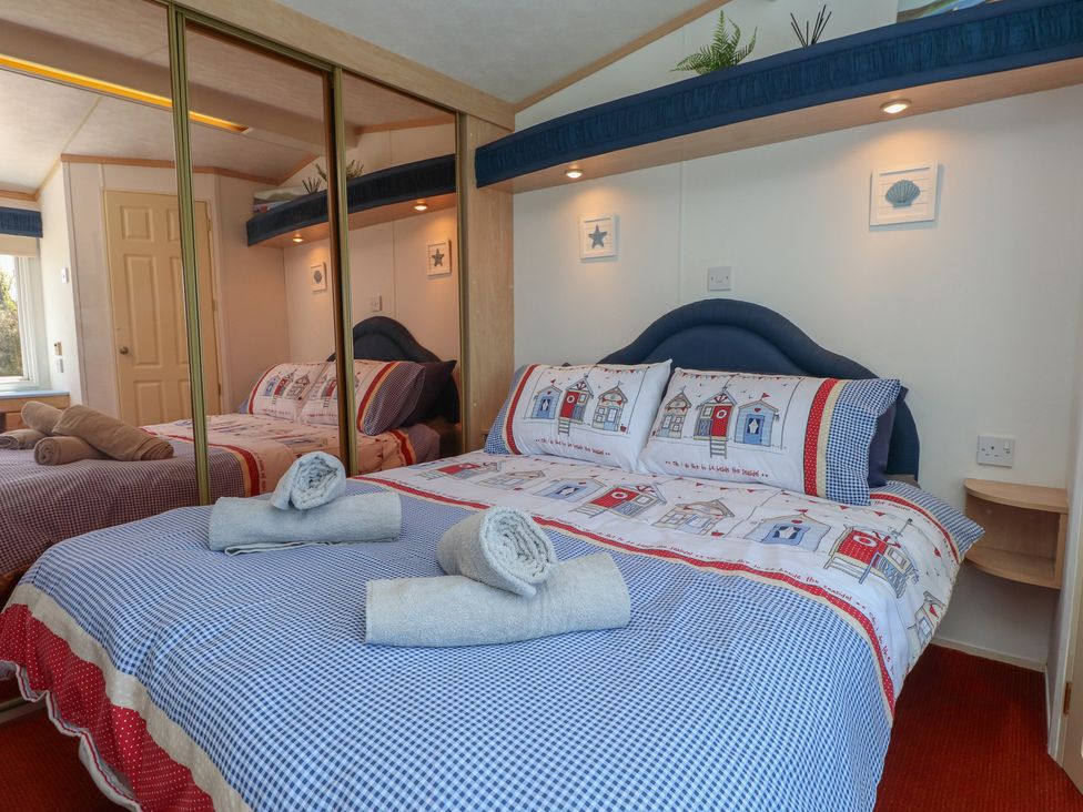 A bedroom with a double bed and towels at Mor a Mynydd in Pwllheli