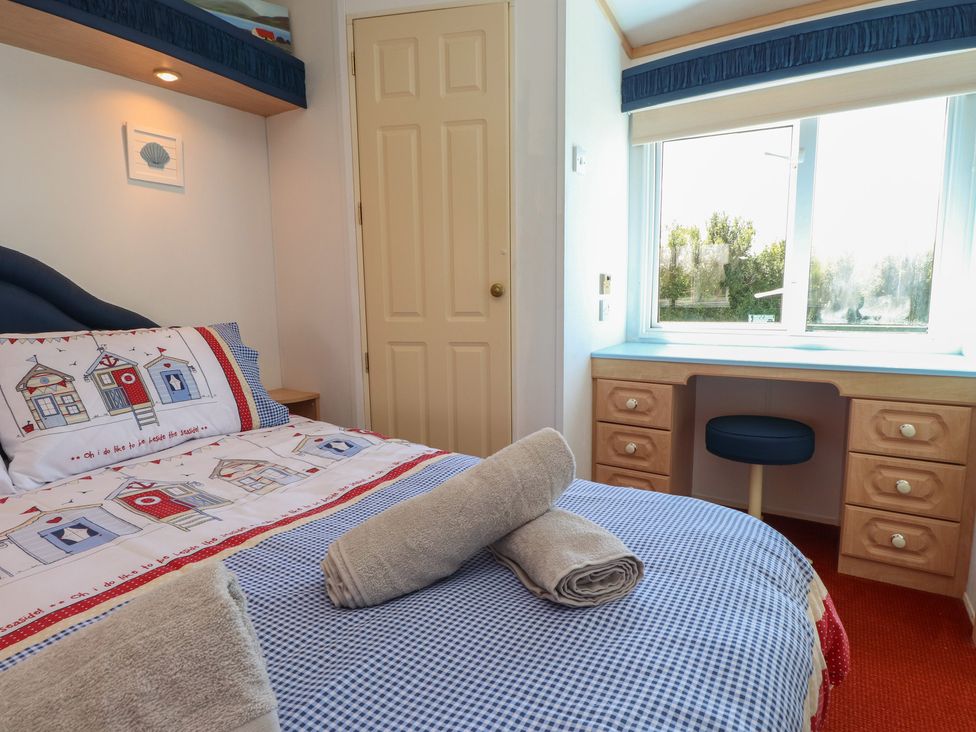 A bedroom with a bed and desk at Mor a Mynydd Pwllheli