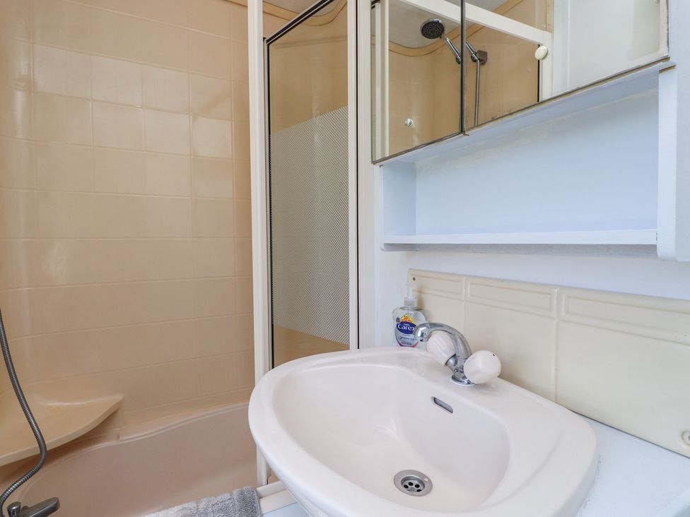 A bathroom with a shower, bathtub, and sink at Mor a Mynydd in Pwllheli