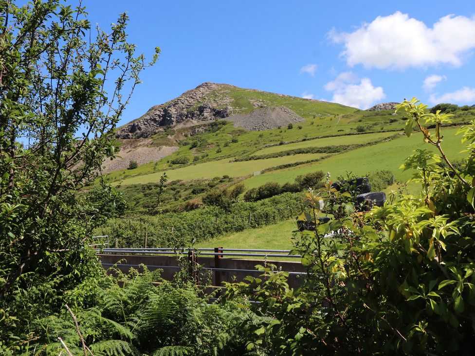 A hillside with a rock formation and greenery at Mor a Mynydd in Pwllheli