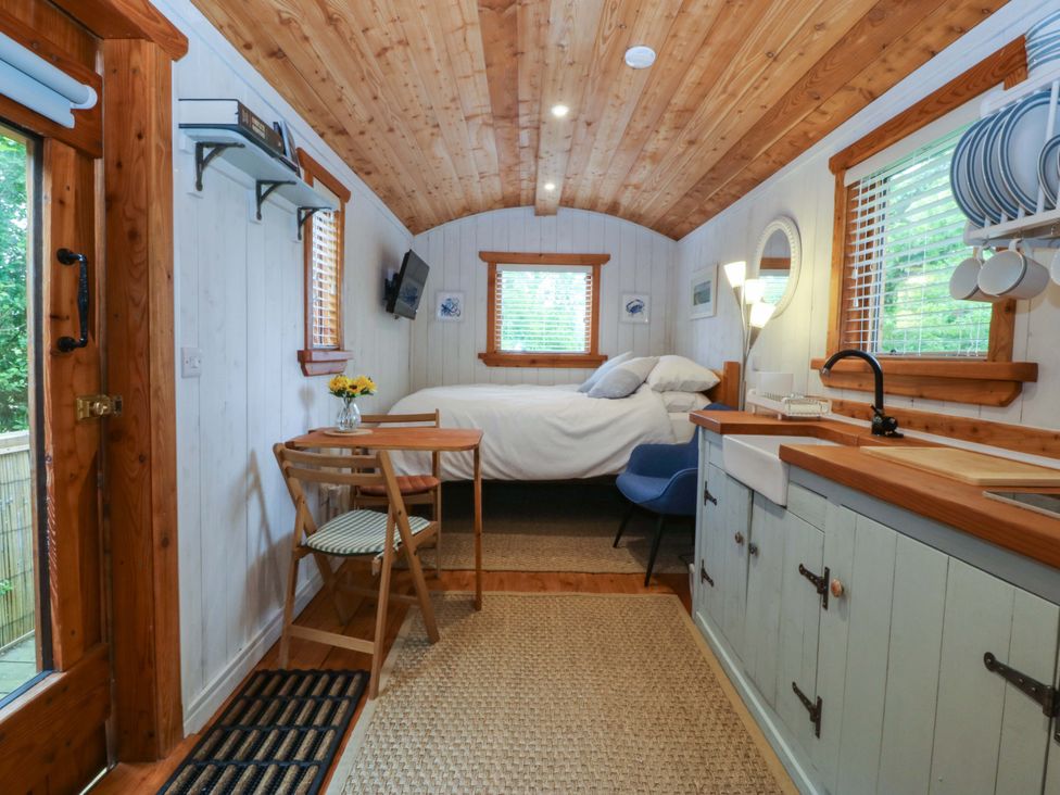 A bedroom with a bed, table, and kitchen area at Ardwyn in Pwllheli