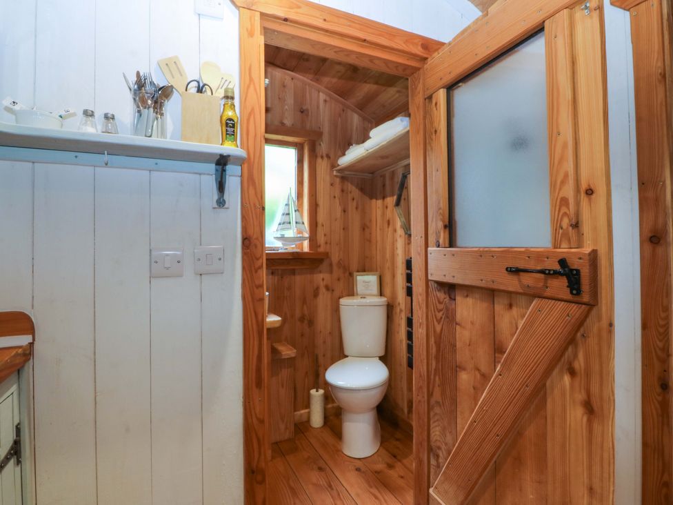 A bathroom featuring a toilet and wooden shelves at Ardwyn Pwllheli