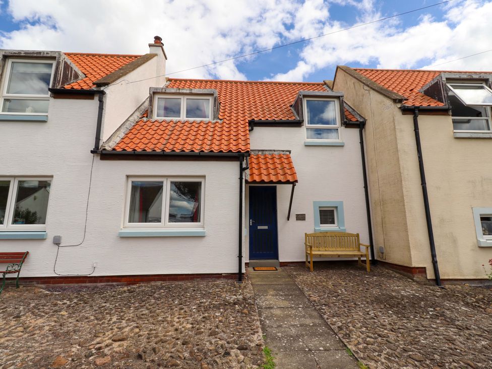 A house with a blue door and a bench in front at Sarah's Cottage