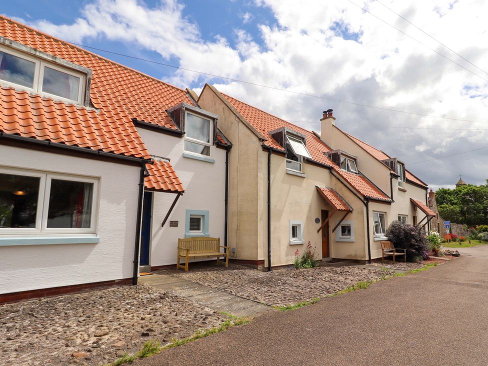 A row of houses with tiled roofs and a bench outside at Sarah's Cottage in 