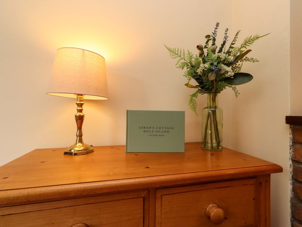 A living room with a lamp and a visitor book at Sarah's Cottage