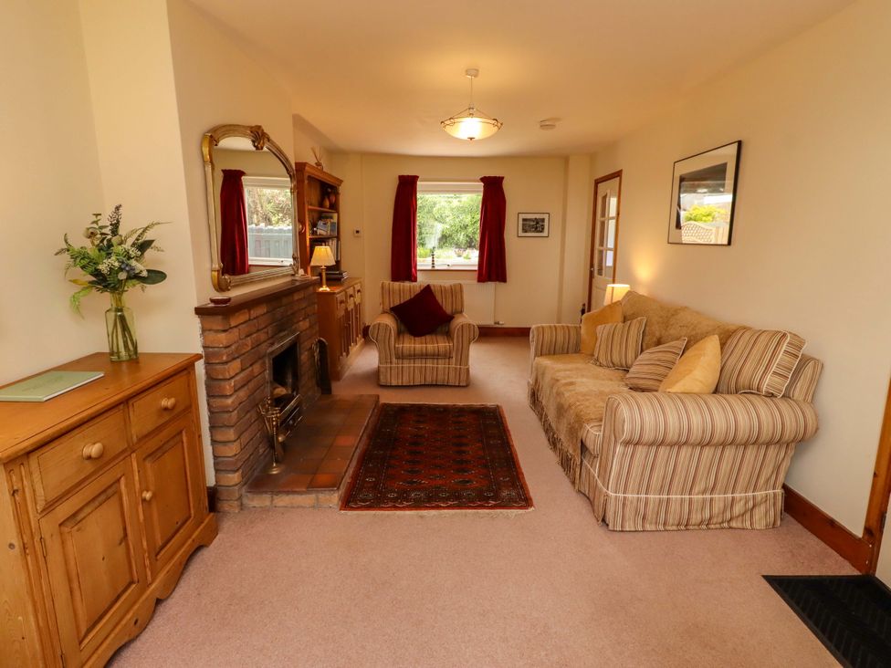 A living room with a sofa, armchair, and fireplace at Sarah's Cottage