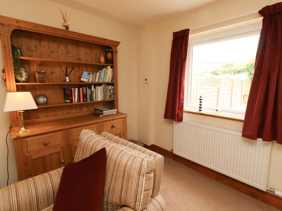 A living room with a bookshelf and sofa at Sarah's Cottage