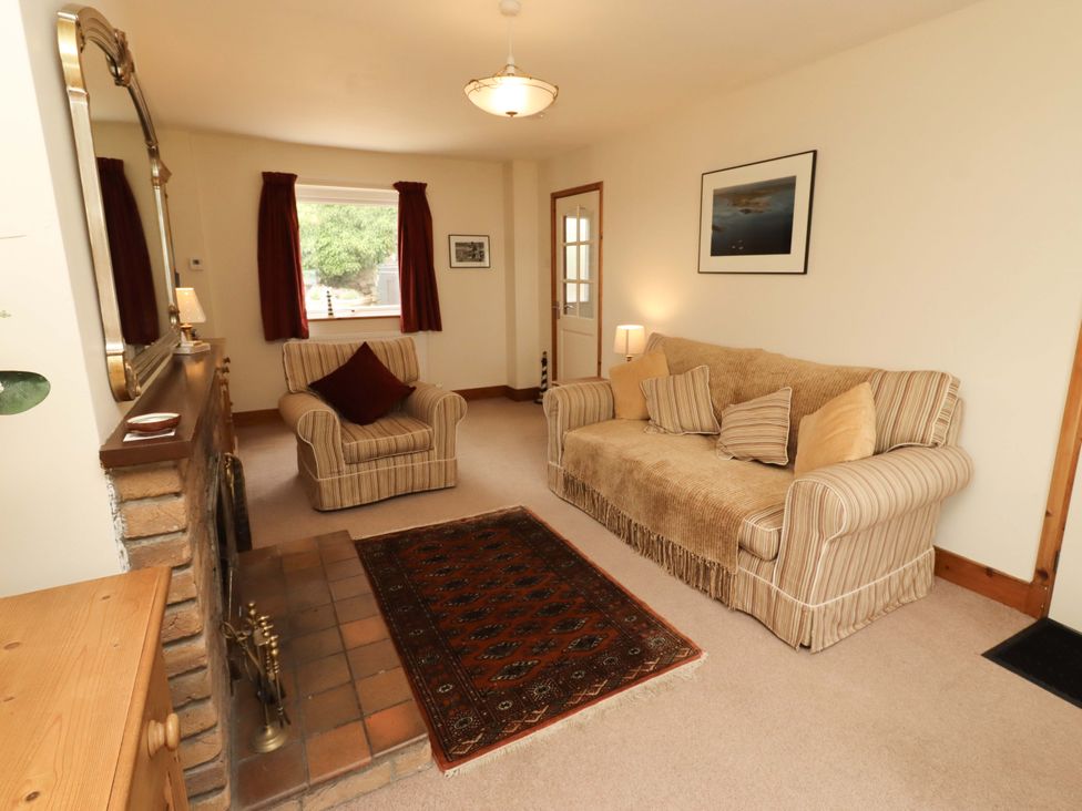 A living room with a sofa and armchair at Sarah's Cottage