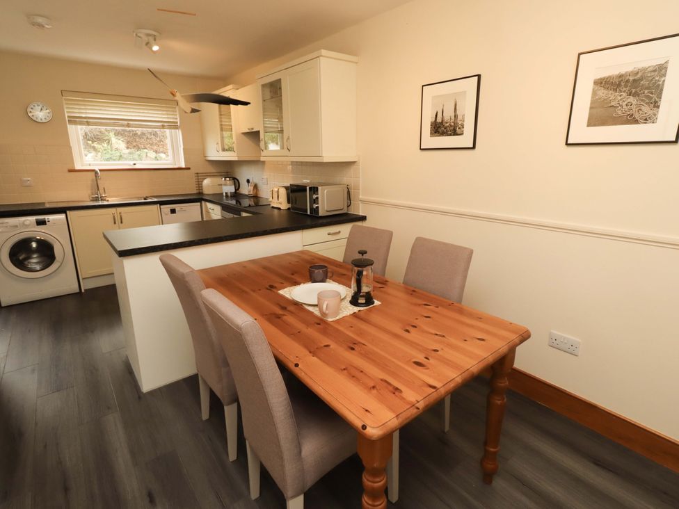 A kitchen with a dining table and appliances at Sarah's Cottage