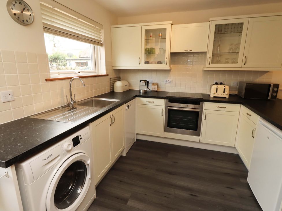 A kitchen with appliances and cabinets at Sarah's Cottage