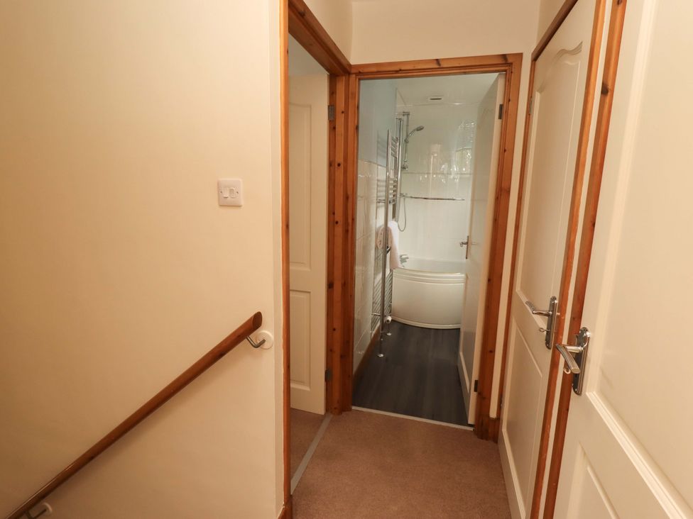 A bathroom with a bathtub and towel rack seen from a hallway at Sarah's Cottage
