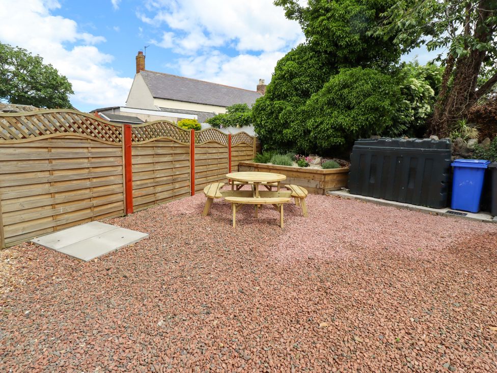 A garden with a table, benches, and bins at Sarah's Cottage