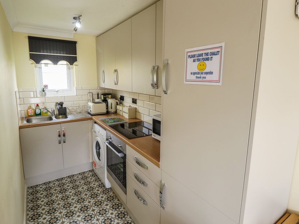 A kitchen with appliances and a notice at Cosy Home Great Yarmouth