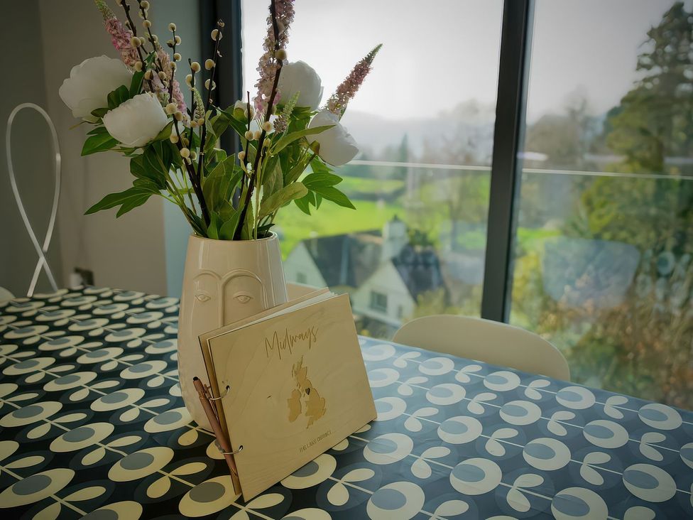 A dining room with a vase and photo album at Midways in Windermere
