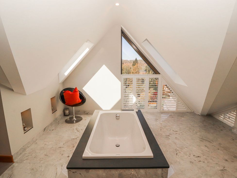 A bathroom with a bathtub and chair at Midways in Windermere