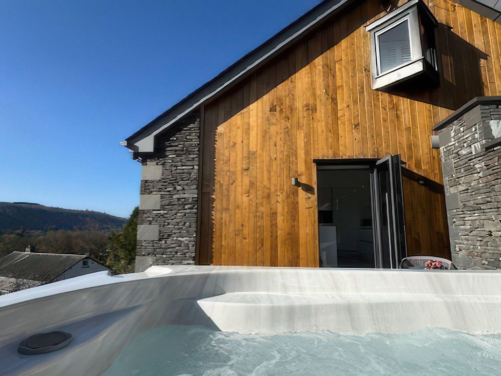 A hot tub near a wooden and stone wall at Midways in Windermere