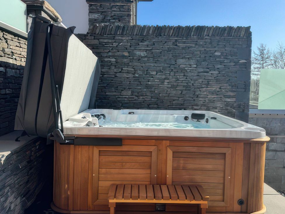 A hot tub with a cover and wooden bench at Midways in Windermere