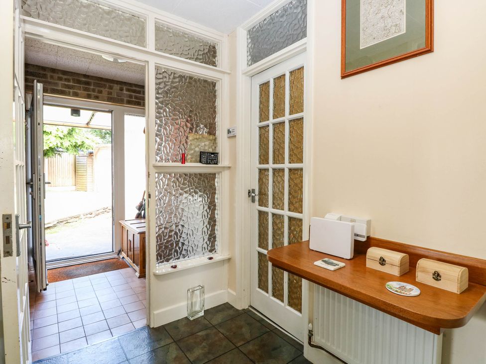 A hallway with a table and door at The Bungalow in Burgh Castle