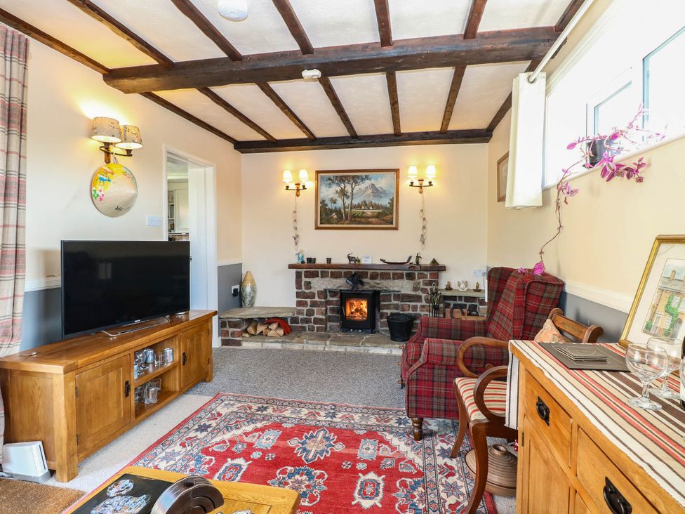A living room with a fireplace and seating area at The Bungalow in Burgh Castle