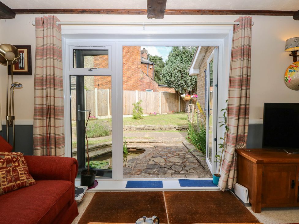 A living room with a view of a garden at The Bungalow in Burgh Castle
