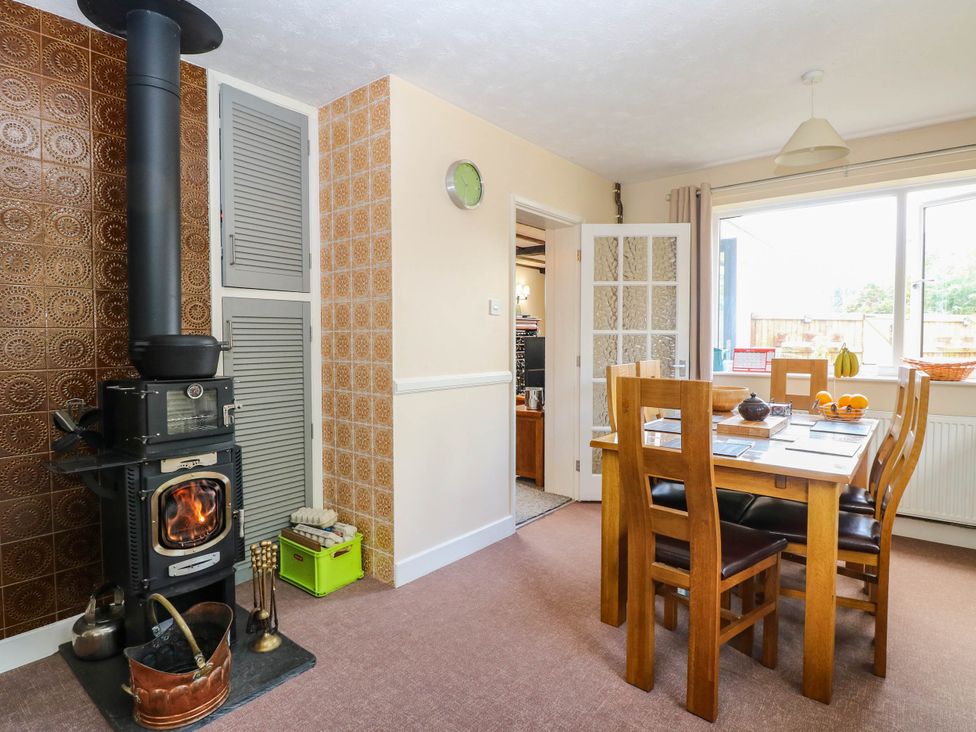 A kitchen with a wood stove and dining table at The Bungalow in Burgh Castle
