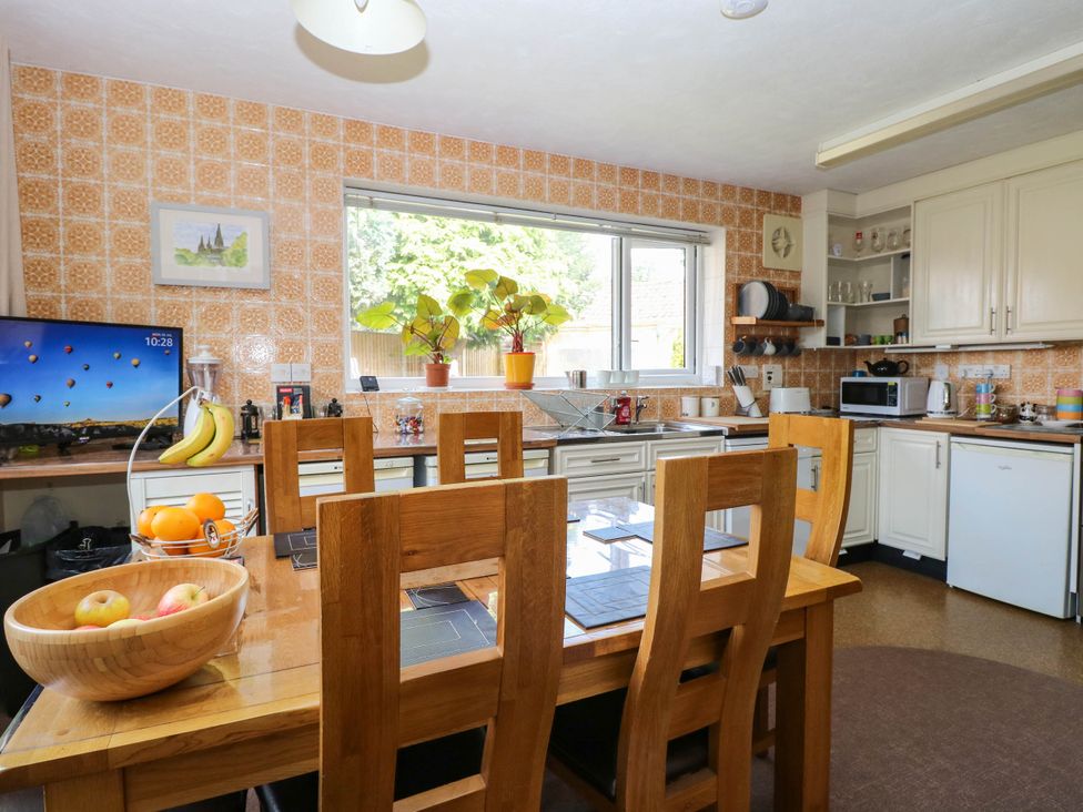 A kitchen with a dining table and television at The Bungalow in Burgh Castle